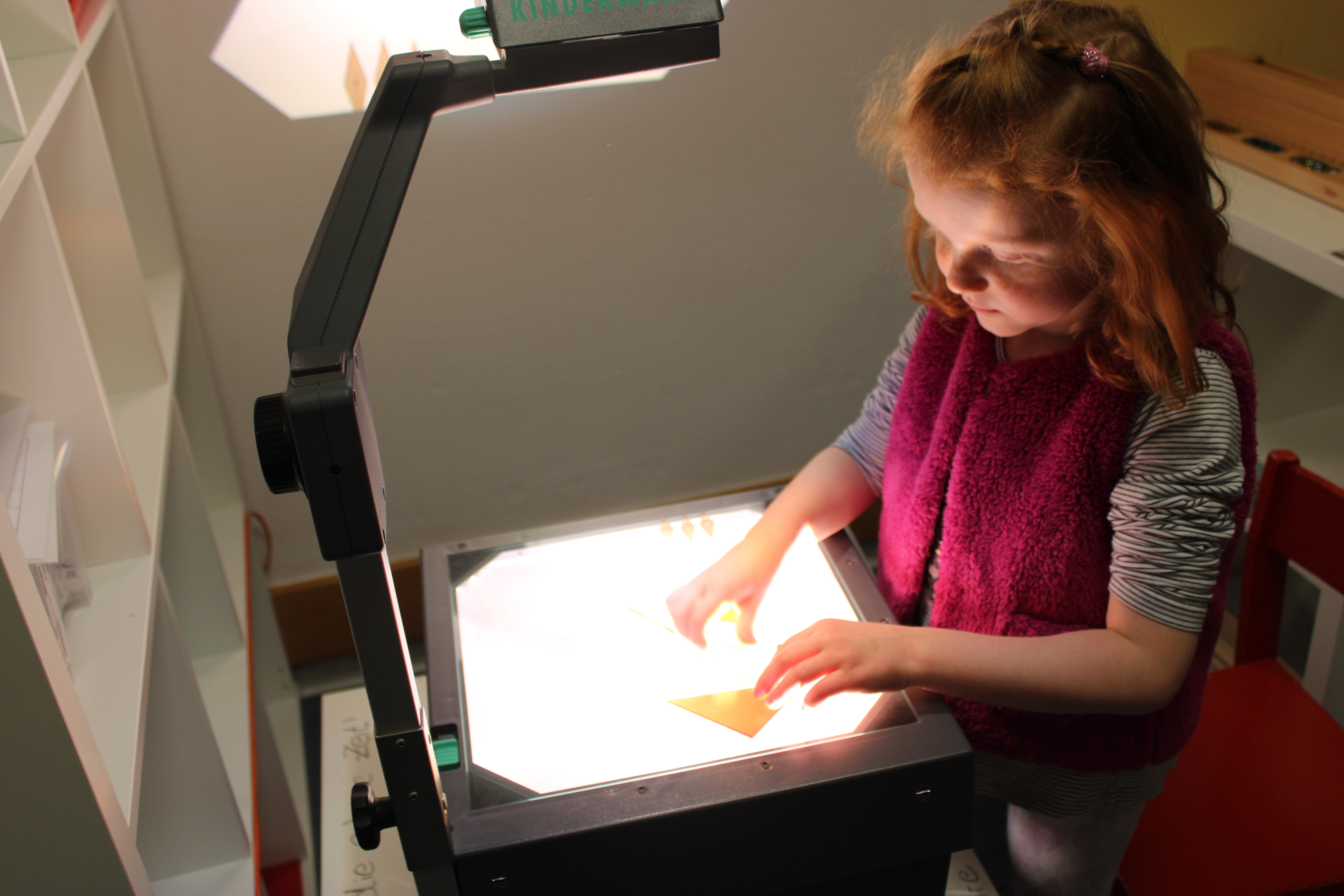 Mädchen legt geometrische Formen auf einen Lichtprojektor